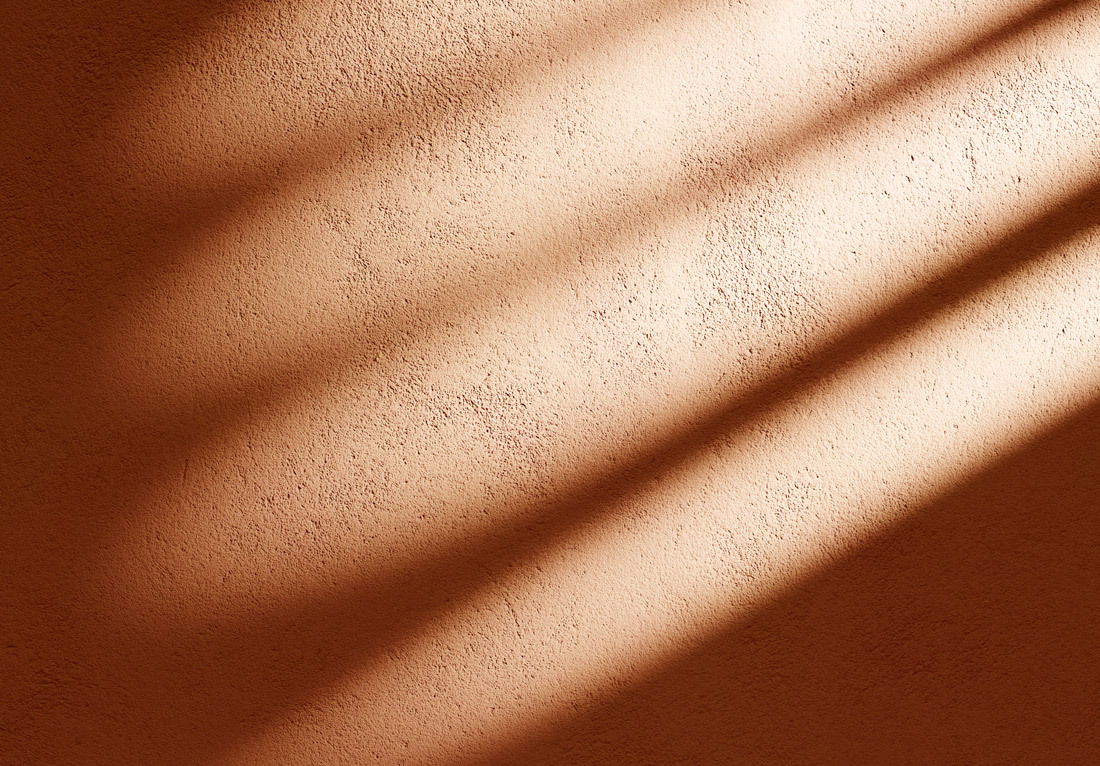 Textured orange concrete wall with sunlight casting diagonal shadows.